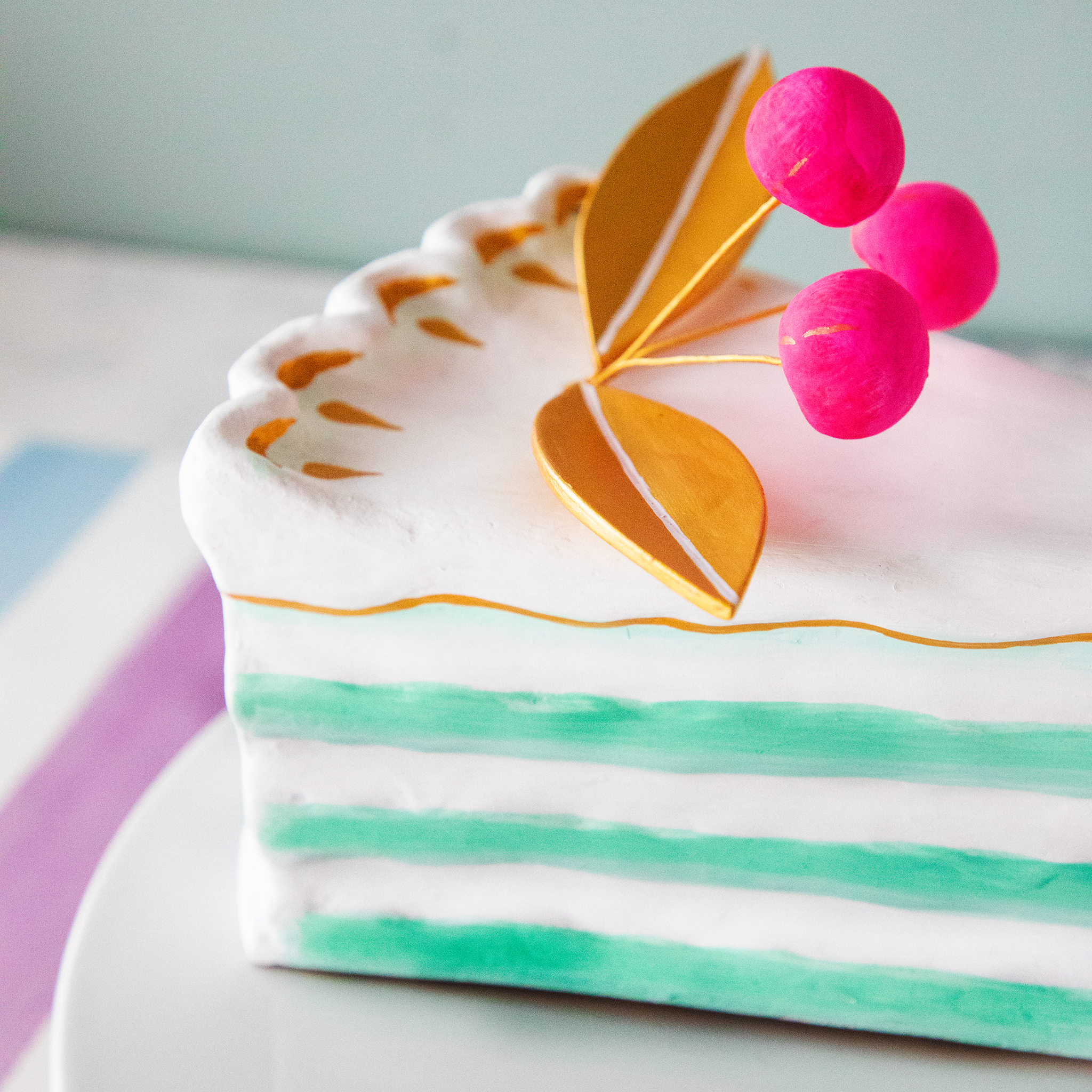 A stack of plates with Glitterville Large French Cake Slices with Gold Leaf on them for a party.