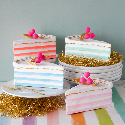 A stack of plates with Glitterville Large French Cake Slices with Gold Leaf on them for a party.