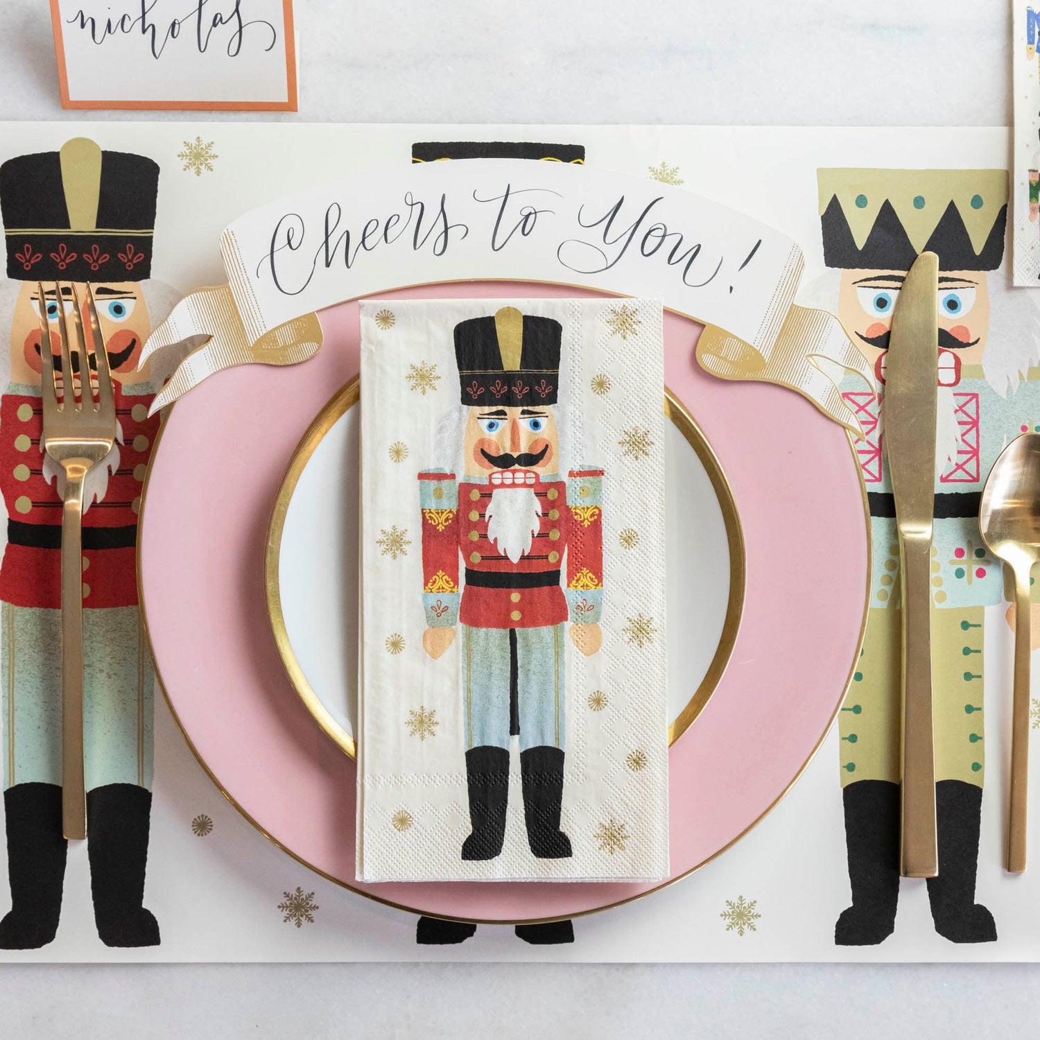 A Nutcracker Guest Napkin centered on the plate of a holiday place setting, from above.