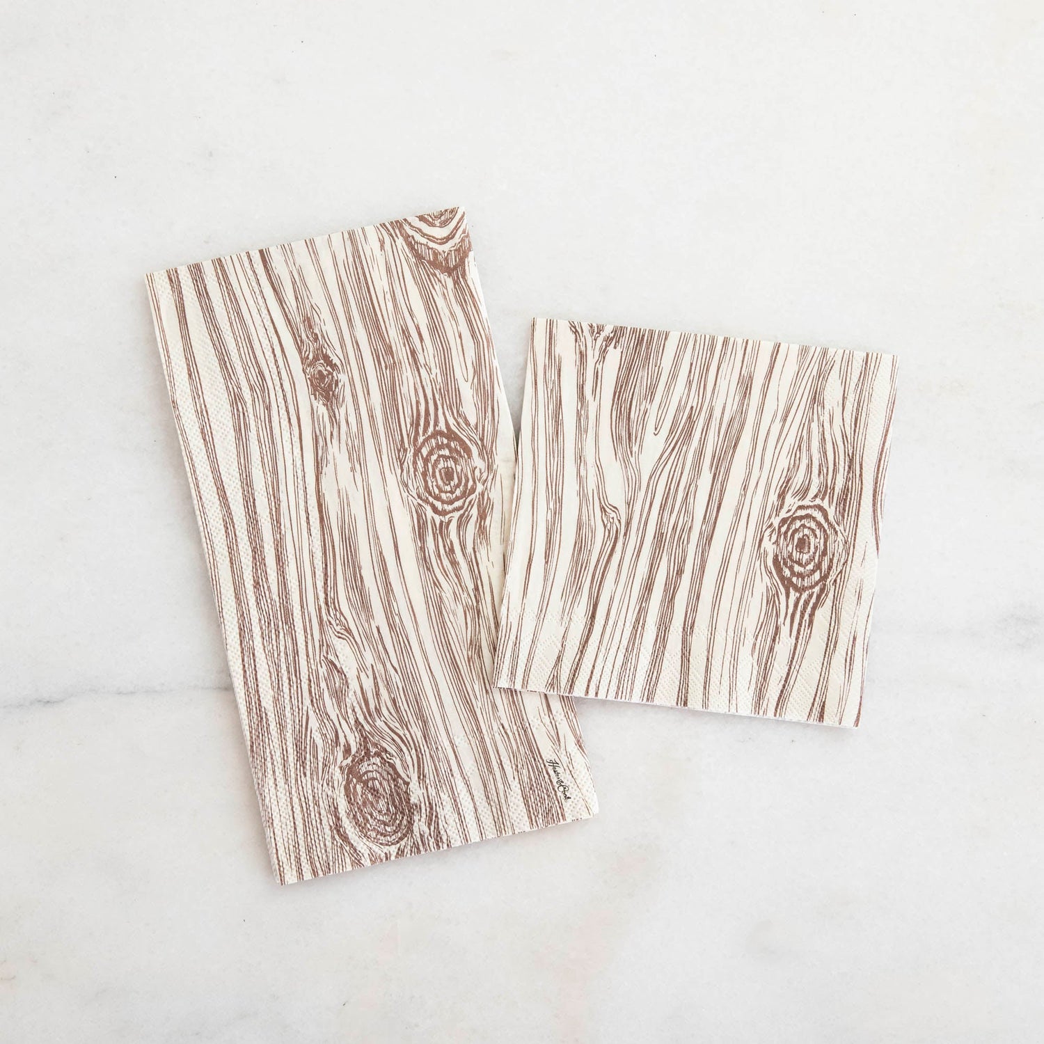 Two Oak Napkins, one Guest and one Cocktail, on a white marble table from above.