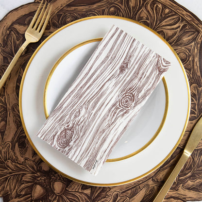 An Oak Guest Napkin centered on a gold-rimmed plate in a rustic place setting.